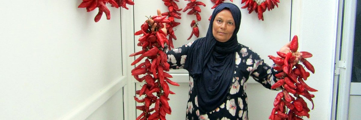 Une productrice de la harissa Errim tenant des guirlandes de piments rouges séchés, à Menzel M'héri